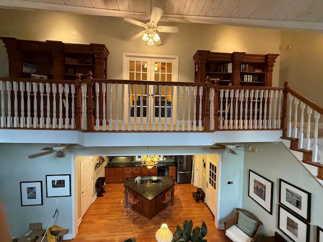 living room with wood ceiling, a towering ceiling, and light hardwood / wood-style floors