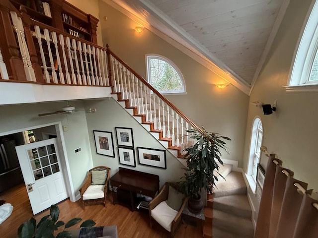 staircase with wooden ceiling, ceiling fan, wood-type flooring, high vaulted ceiling, and ornamental molding