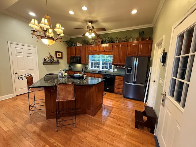 kitchen with ornamental molding, black appliances, ceiling fan with notable chandelier, a breakfast bar, and sink