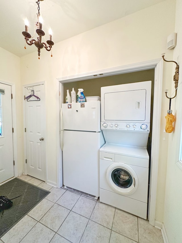 laundry area with light tile patterned floors, stacked washer and clothes dryer, and an inviting chandelier