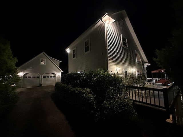 property exterior at night featuring a garage and an outbuilding