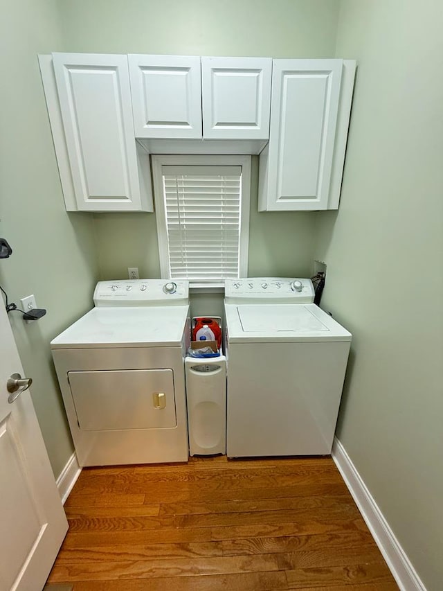 laundry area with washer and dryer, hardwood / wood-style flooring, and cabinets