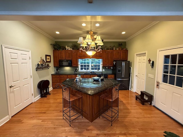 kitchen featuring black appliances, a kitchen bar, an inviting chandelier, sink, and crown molding