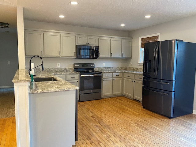 kitchen featuring appliances with stainless steel finishes, light hardwood / wood-style floors, sink, kitchen peninsula, and gray cabinetry