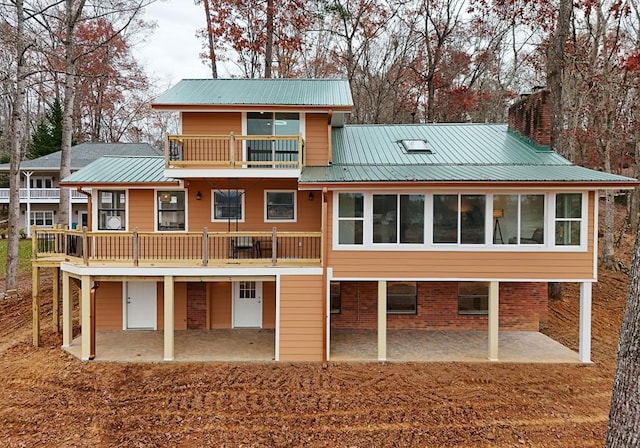 back of property featuring metal roof, a patio, brick siding, and a chimney