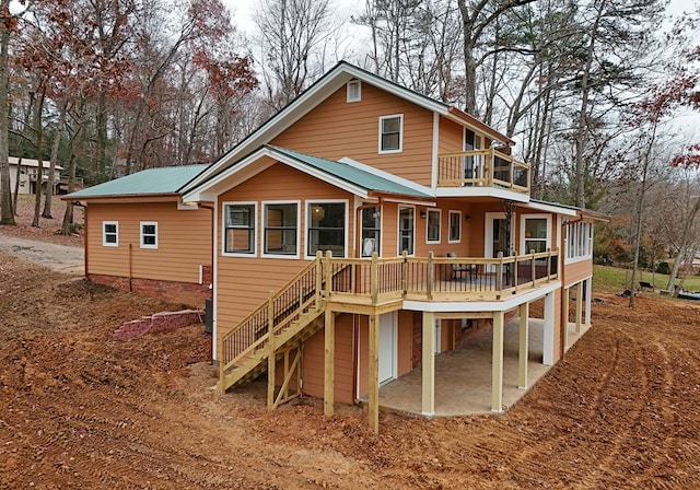 back of property featuring a balcony and a wooden deck