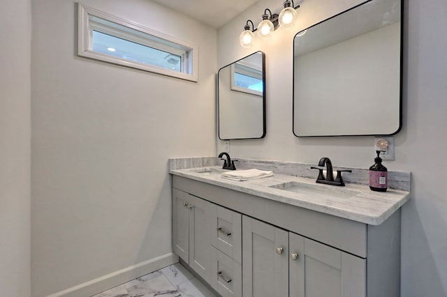 bathroom featuring marble finish floor, double vanity, a sink, and baseboards