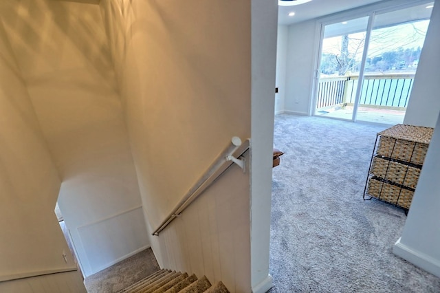 staircase featuring carpet floors, a water view, and baseboards