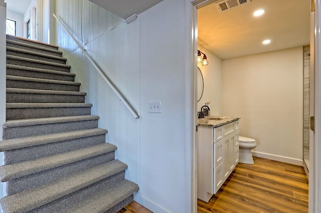 stairway with recessed lighting, visible vents, baseboards, and wood finished floors