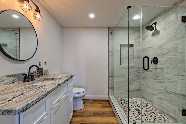 bathroom featuring baseboards, toilet, wood finished floors, vanity, and a shower stall