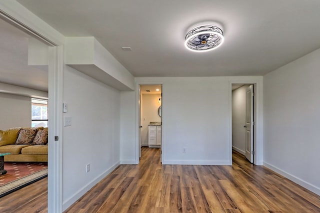 bedroom with ensuite bathroom, baseboards, and wood finished floors