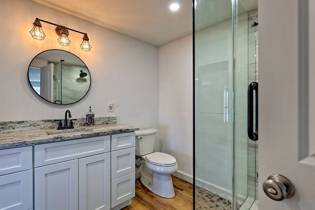 full bathroom with vanity, a shower stall, toilet, and wood finished floors