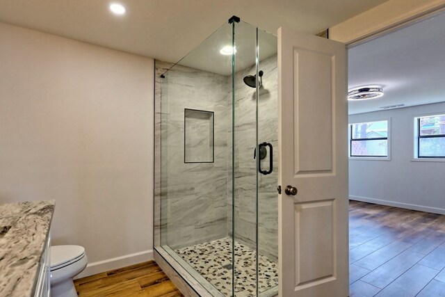 full bathroom featuring toilet, a stall shower, baseboards, and wood finished floors