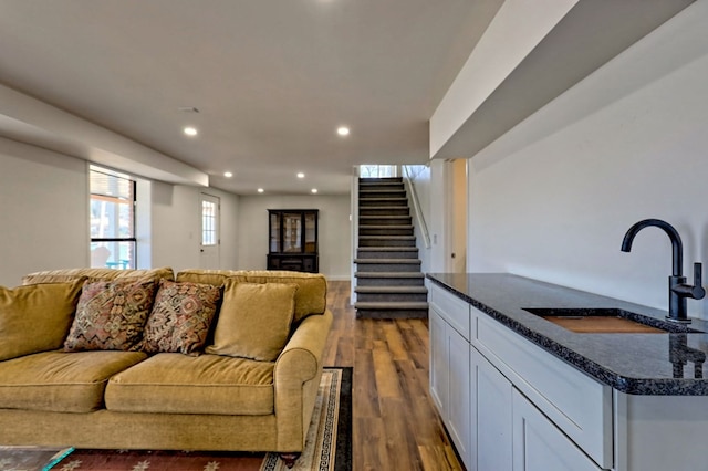 living room featuring recessed lighting, dark wood finished floors, and stairway