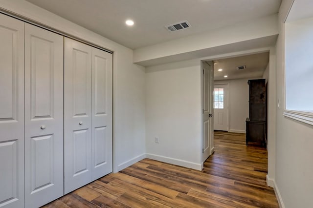 hall with wood finished floors, visible vents, and baseboards