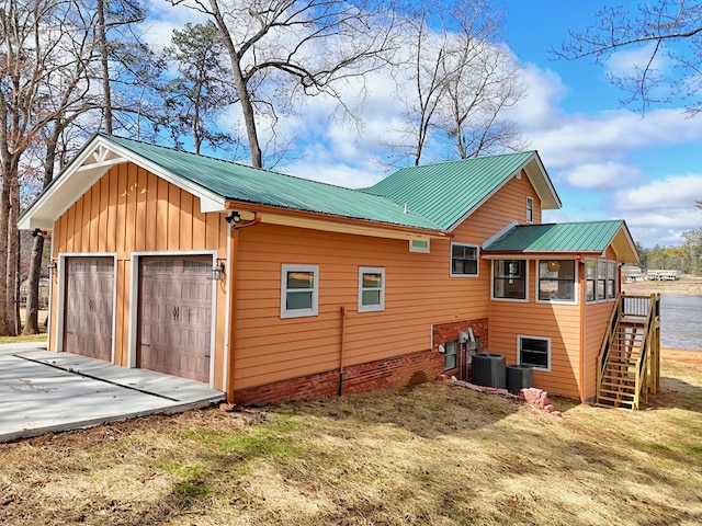 view of side of property with stairs, metal roof, central AC unit, and board and batten siding