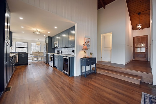 kitchen with dark wood-type flooring, decorative backsplash, a notable chandelier, stainless steel appliances, and beverage cooler