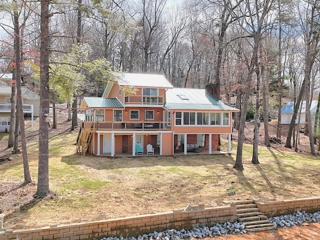 rear view of property with a sunroom, stairs, metal roof, and a wooden deck