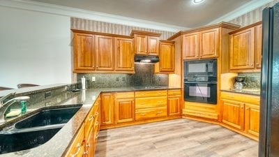 kitchen with decorative backsplash, ornamental molding, sink, black appliances, and light hardwood / wood-style floors