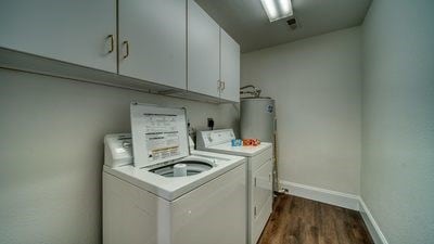 washroom featuring electric water heater, dark hardwood / wood-style flooring, cabinets, and separate washer and dryer