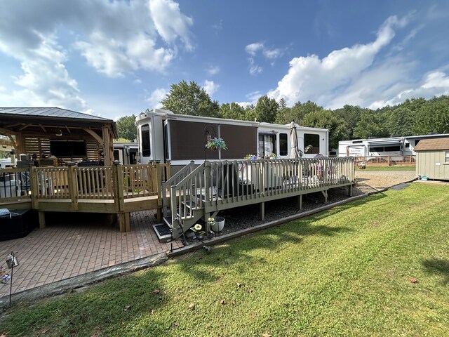 back of house featuring ceiling fan, a deck, a patio, and a lawn