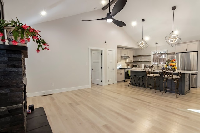 kitchen featuring pendant lighting, a center island, a kitchen bar, light hardwood / wood-style flooring, and stainless steel appliances