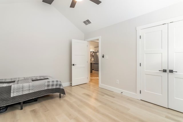 bedroom with ceiling fan, vaulted ceiling, stainless steel refrigerator, light hardwood / wood-style flooring, and a closet