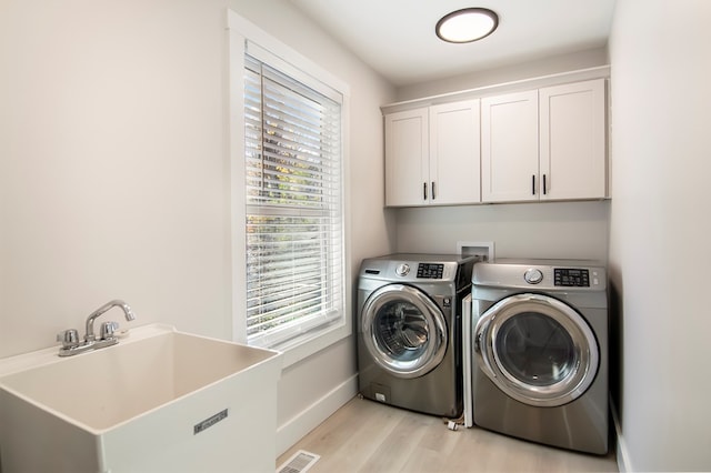 washroom with cabinets, sink, separate washer and dryer, and light hardwood / wood-style flooring