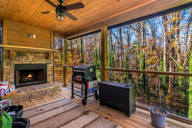 sunroom featuring wooden ceiling, an outdoor stone fireplace, and ceiling fan