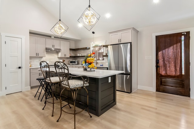 kitchen featuring decorative backsplash, pendant lighting, gray cabinets, and stainless steel refrigerator