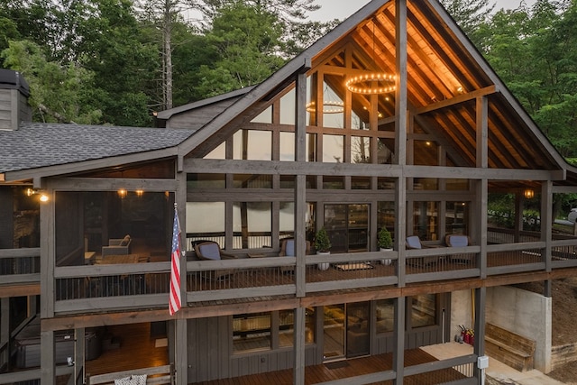 rear view of house with roof with shingles and a sunroom