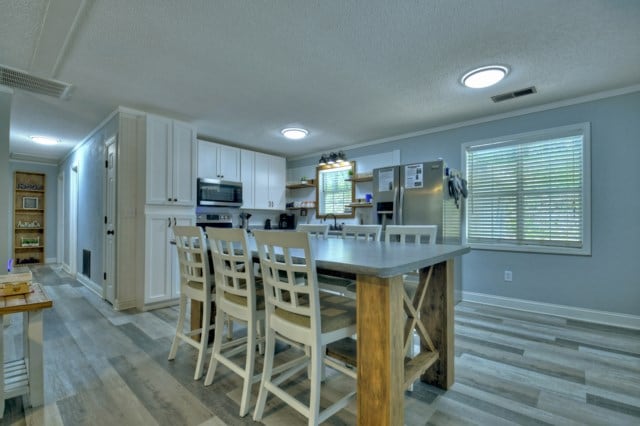 151 Padget Ln, Ellijay, GA 30540 - kitchen featuring appliances with stainless steel finishes, a textured ceiling, white cabinetry, open shelves, and ornamental molding