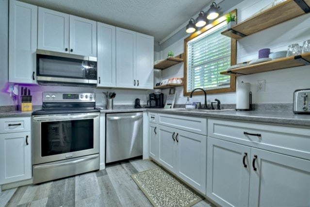 151 Padget Ln, Ellijay, GA 30540 - kitchen with open shelves, stainless steel appliances, a sink, white cabinetry, and a textured ceiling