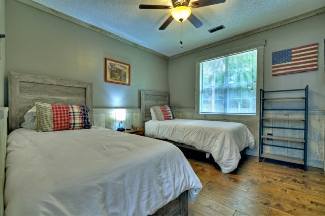 151 Padget Ln, Ellijay, GA 30540 - bedroom with hardwood / wood-style flooring, a textured ceiling, a wainscoted wall, and ceiling fan