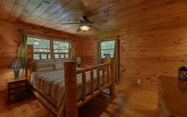 bedroom with ceiling fan, wood walls, light hardwood / wood-style flooring, and multiple windows