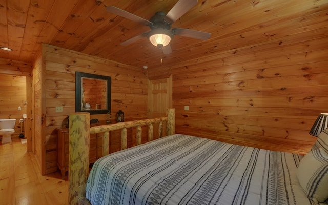 bedroom with ceiling fan, wooden walls, wooden ceiling, connected bathroom, and light hardwood / wood-style floors