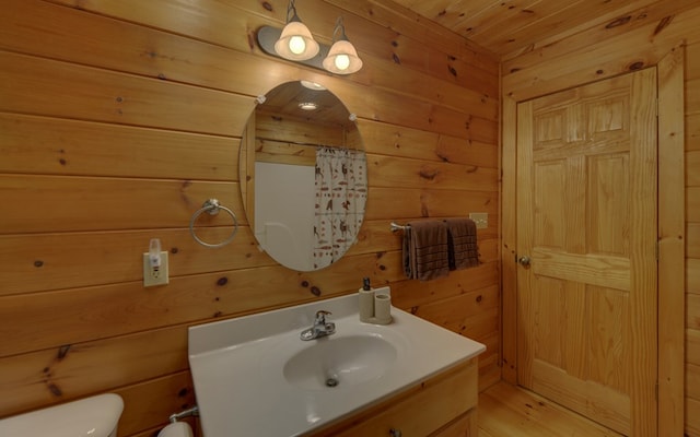 bathroom featuring vanity, wooden walls, toilet, walk in shower, and wood ceiling