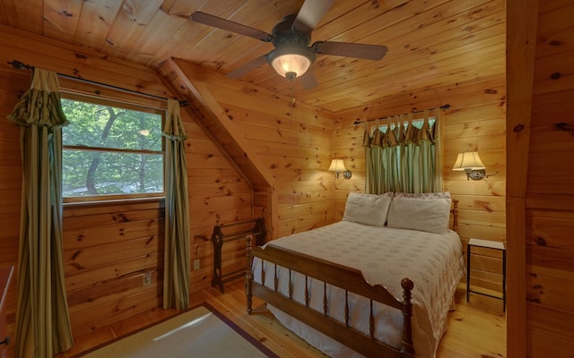 bedroom with ceiling fan, wood walls, light hardwood / wood-style floors, and lofted ceiling