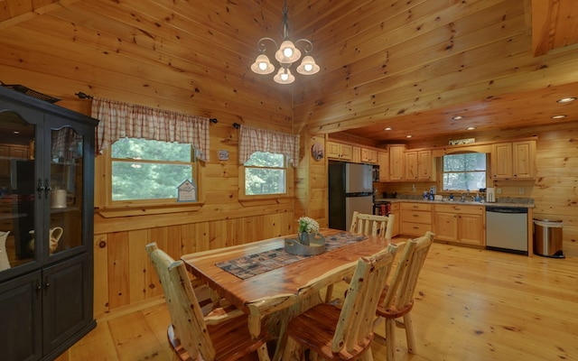 dining room featuring wooden walls, light hardwood / wood-style flooring, a chandelier, and sink