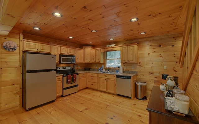 kitchen with sink, light brown cabinets, wood walls, light hardwood / wood-style floors, and appliances with stainless steel finishes