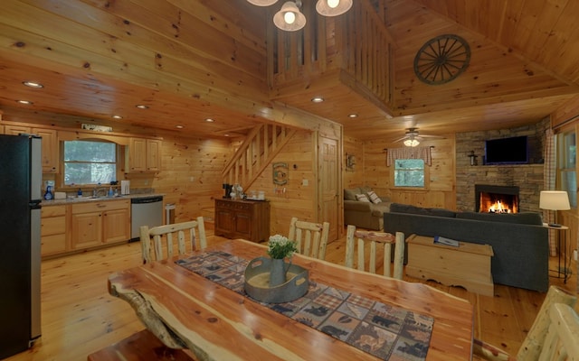 dining room with wood walls, sink, a fireplace, light hardwood / wood-style floors, and wood ceiling