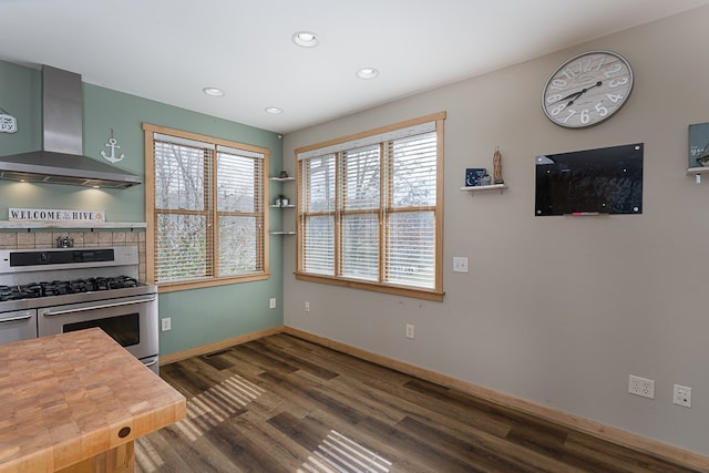 kitchen with stainless steel gas stove, dark wood-type flooring, wall chimney range hood, and wood counters