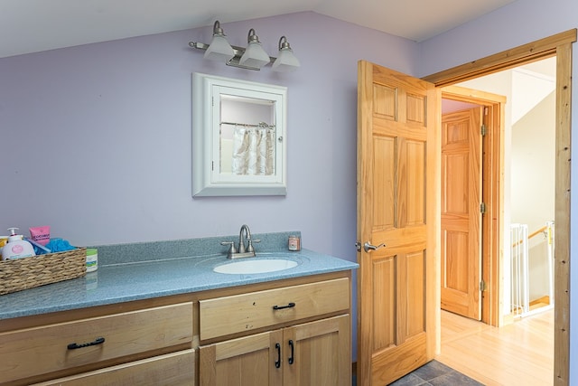 bathroom featuring vanity, lofted ceiling, and wood-type flooring