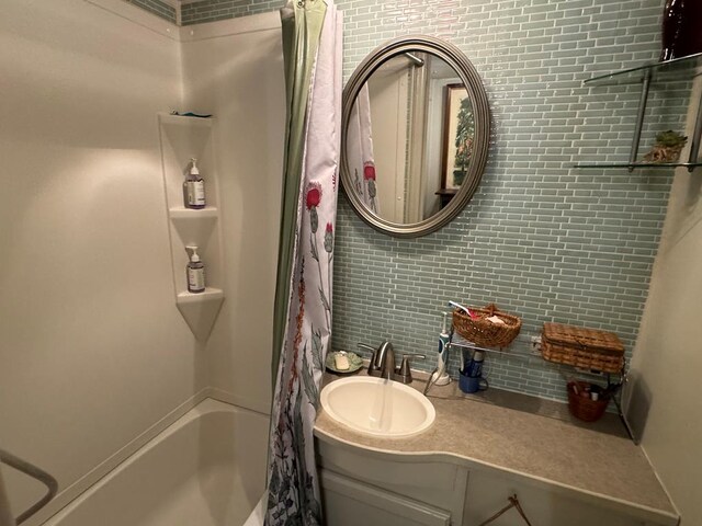 bathroom featuring shower / bath combo, vanity, and tasteful backsplash