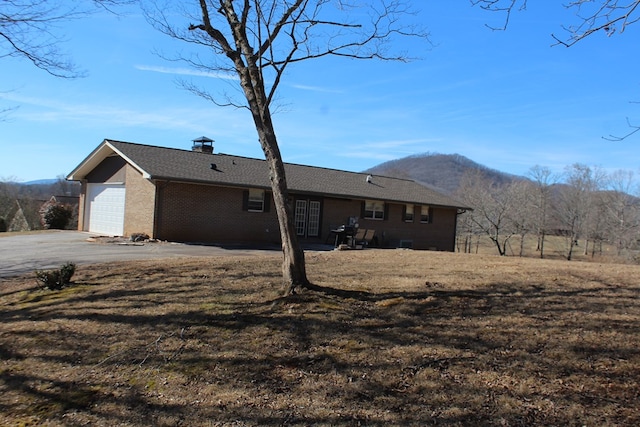 exterior space with a garage, a mountain view, and a lawn