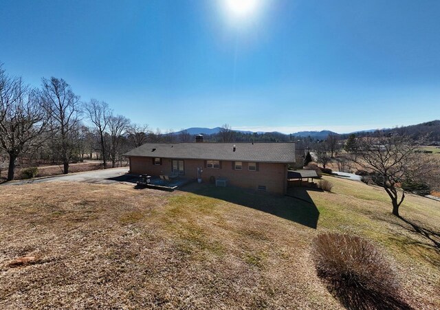 view of side of property with a mountain view and a yard