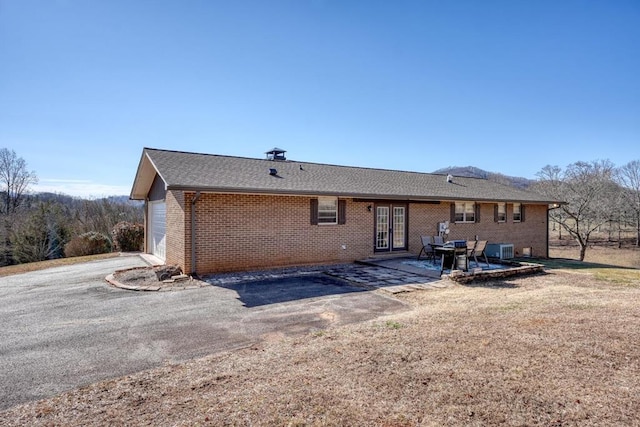 rear view of property with a garage and a patio area