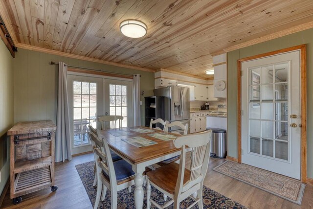 dining space with crown molding, light hardwood / wood-style floors, wood ceiling, and french doors