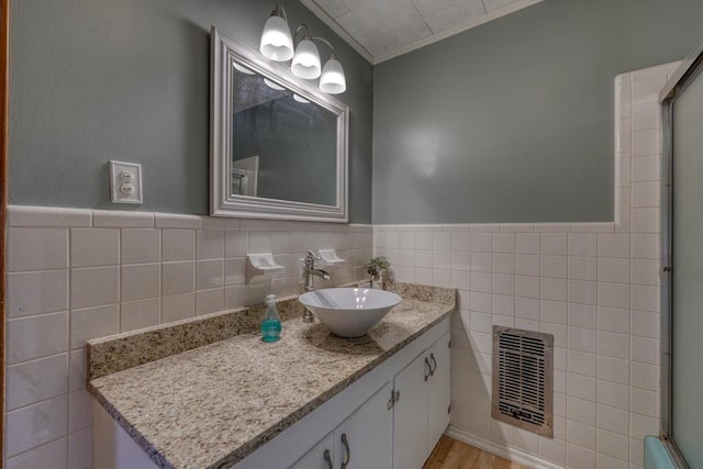 bathroom with hardwood / wood-style flooring, ornamental molding, vanity, and tile walls