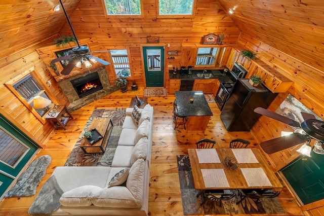 living room with wooden walls, high vaulted ceiling, and ceiling fan